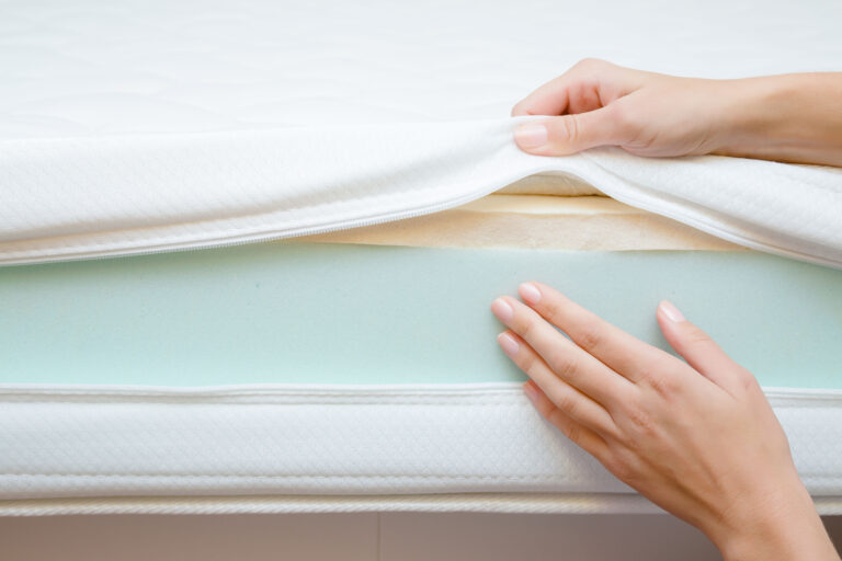 Woman's hands touching different layers of new mattress. Checking hardness and softness.